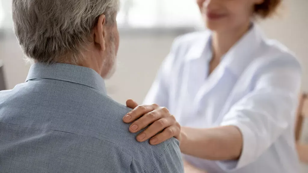A support worker placing a reassuring hand on a service user's shoulder